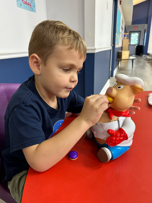 Boy playing "Pop the Pig" at preschool during a speech therapy session.