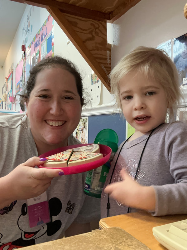 Speech therapist and little girl pretending to cook pizza during a therapy session at preschool.
